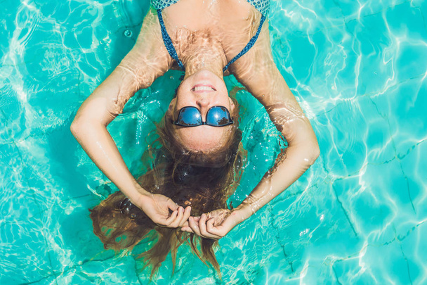 young woman floating in pool  - 写真・画像