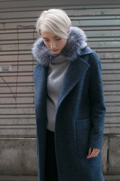 Une fille blonde avec des lunettes et un manteau parcourt les rues de la ville
 - Photo, image