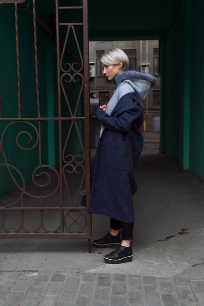 Une fille blonde avec des lunettes et un manteau parcourt les rues de la ville
 - Photo, image