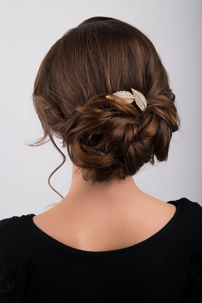 Assembled formal hairstyle dark hair decorated with a crest in the form of sheets, back view - Foto, imagen