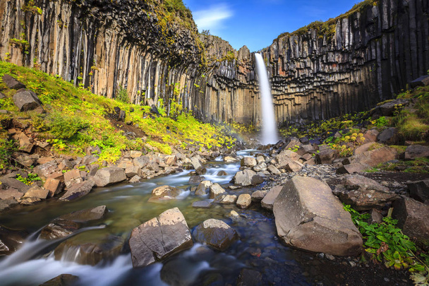 cascada rodeada de columnas de basalto
  - Foto, Imagen
