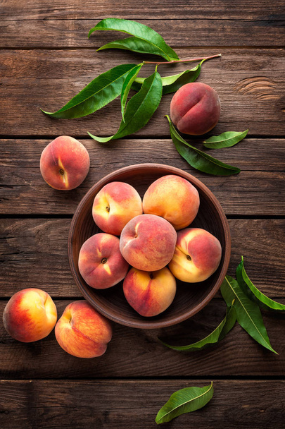 Fresh juicy peaches with leaves on dark wooden rustic background - Valokuva, kuva