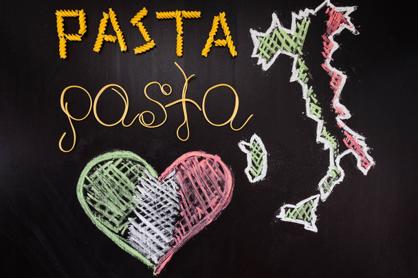 Words pasta made of cooked spaghetti and dry pasta on the black background with frame of country Italy and heart are written by chalk and forks - 写真・画像