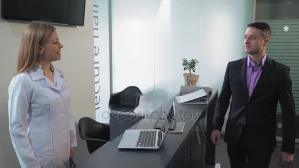 Worker in clinic speaking with client. - Materiał filmowy, wideo