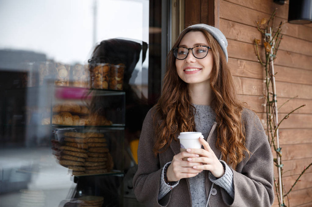 Happy woman drinking coffee outdoors in autumn - Photo, Image