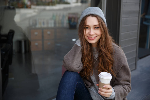 Smiling attractive young woman drinking coffee-to-go in the city - Foto, immagini