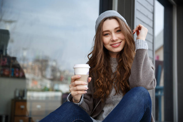 Smiling woman resting and drinking coffee outdoors in the city - Φωτογραφία, εικόνα