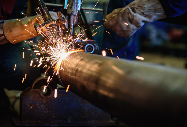 Tubo d'acciaio di taglio del lavoratore con la torcia di taglio della saldatura dell'acetilene e scintille luminose nell'industria edile d'acciaio
. - Foto, immagini