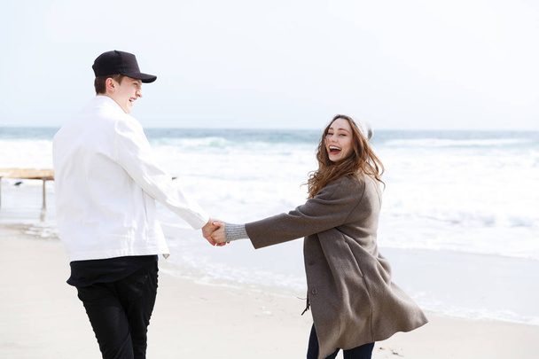 Couple walking and laughing on the beach in autumn - Foto, Imagen