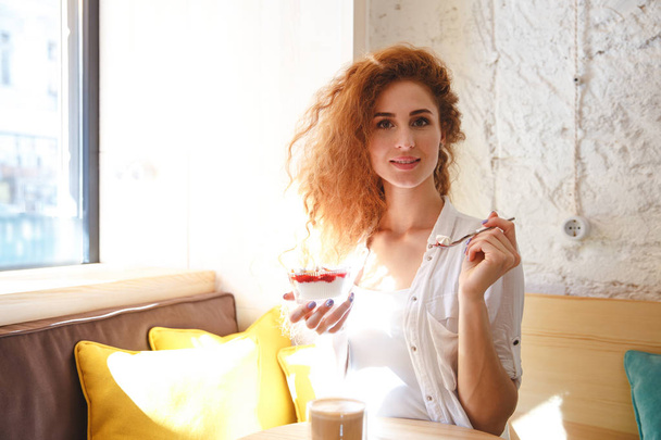 Amazing redhead young lady sitting in cafe while eating dessert - Photo, Image