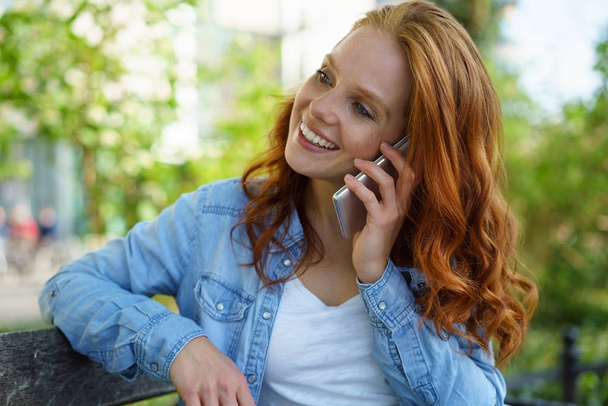 Gorgeous young redhead woman chatting on a mobile - Fotó, kép