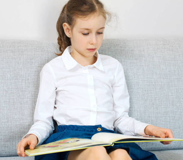 Χαριτωμένο κοριτσάκι που διαβάζει ένα βιβλίο. - Φωτογραφία, εικόνα
