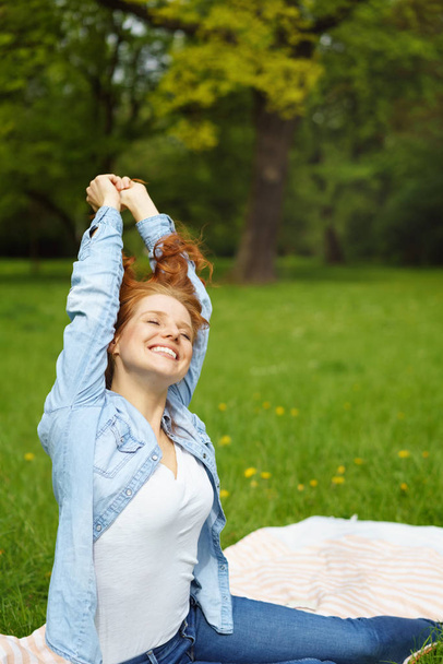Happy relaxed young woman stretching in a park - Foto, immagini
