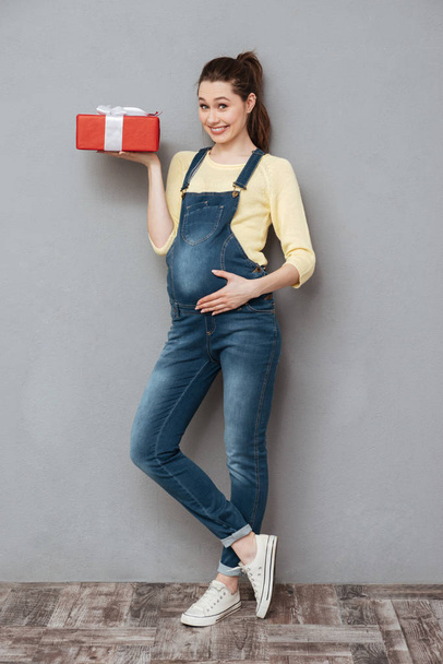 Pregnant happy lady holding gift. - 写真・画像