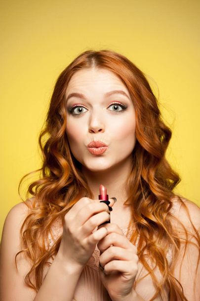 young redhead woman holding lipstick - Foto, afbeelding