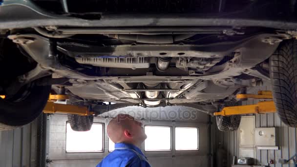 Maschio meccanico esame sollevato parti di automobili in officina di riparazione auto
 - Filmati, video