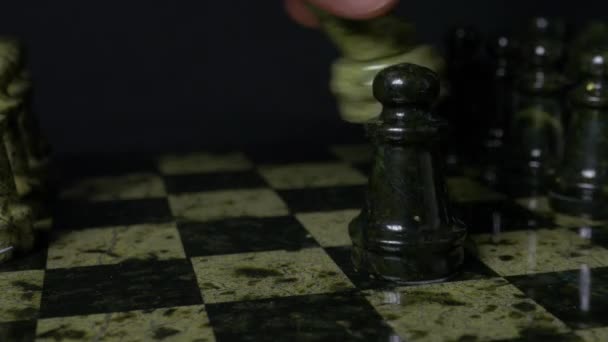 Ghess white horse defeats black pawn. Selective focus. Chess, Horse and pawn. Details of chess piece on black background. - Footage, Video