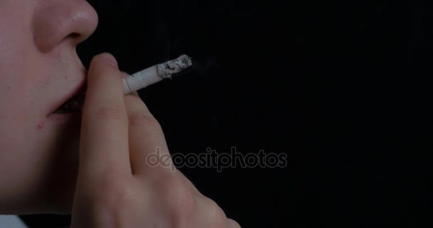 Az ember a dohányzás cigaretta fekete háttér. Cigaretta a dohányzás fiatalember portréja közelről. A dohányzás. Egy fiatal férfi, cigarettázott - Felvétel, videó