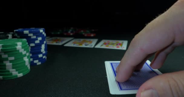 Osoba, ukazující jeho palubu v pokeru. Karetní hráč kontroluje že ruku, dvě esa, čipy v pozadí na zelené hrát stůl, zaměření na kartě. Ruka dvě esa v pokeru - Záběry, video