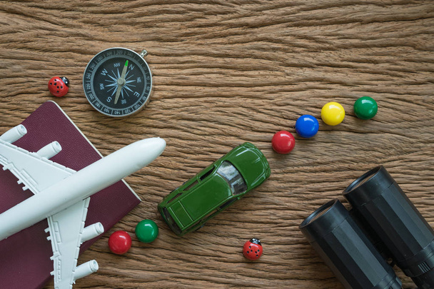 airplane, passport, compass, binoculars and miniature car on woo - 写真・画像