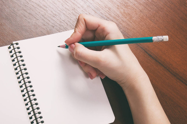 Closeup photo of girl writing in notebook with pencil - Foto, Bild