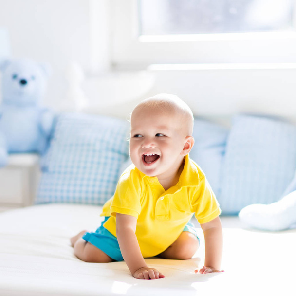 Baby boy playing on bed in sunny nursery - Photo, Image