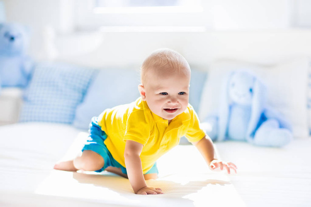 Baby boy playing on bed in sunny nursery - Photo, Image