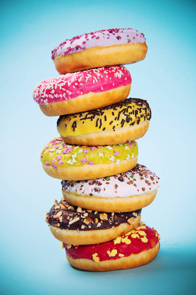 Donuts glazed with sprinkles on light blue background - Foto, afbeelding