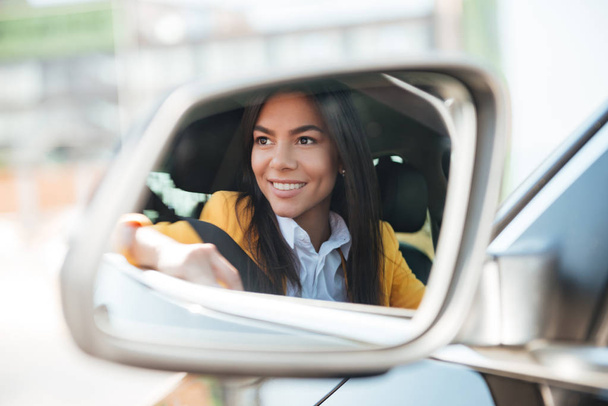 Smiling business woman in side view car mirror - Foto, Imagen