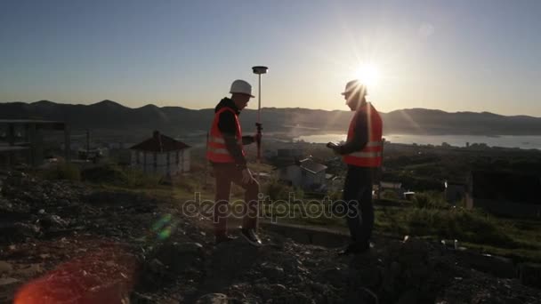 Dos topógrafos en cascos que realizan mediciones geodésicas en la cima de la montaña
 - Metraje, vídeo