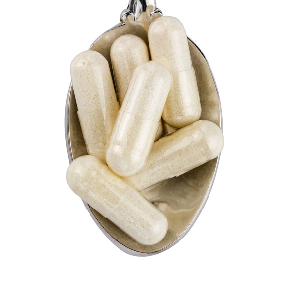 Capsules van glucosamine chondroïtine, gezonde supplement pillen in de lepel geïsoleerd op witte achtergrond, bovenaanzicht. - Foto, afbeelding