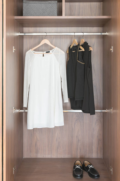 conjunto de roupas pretas e brancas penduradas no trilho
  - Foto, Imagem