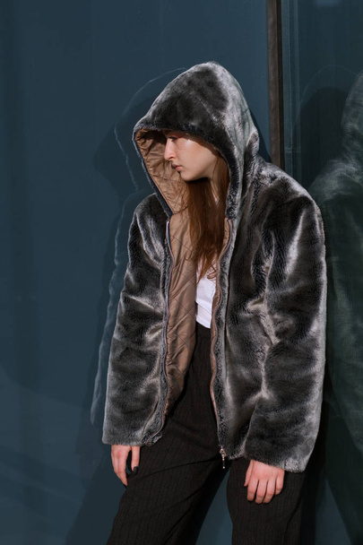 Uma menina bonita e elegante em um casaco de peles caminha na cidade em um dia ensolarado
 - Foto, Imagem