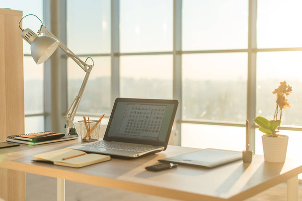Foto vista lateral do local de trabalho do estúdio com notebook em branco, laptop. Mesa de trabalho confortável, escritório em casa
. - Foto, Imagem