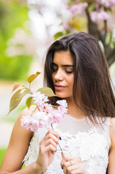 Mulher caucasiana positiva alegre posando com árvore sakura florido
. - Foto, Imagem