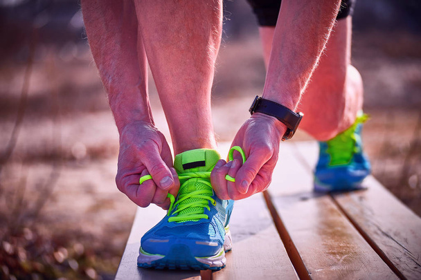 Завязывать шнурки на кроссовках во время занятий спортом на открытом воздухе
. - Фото, изображение