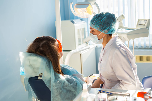Woman dentist in the medical dental office. She is heals patient - Fotoğraf, Görsel