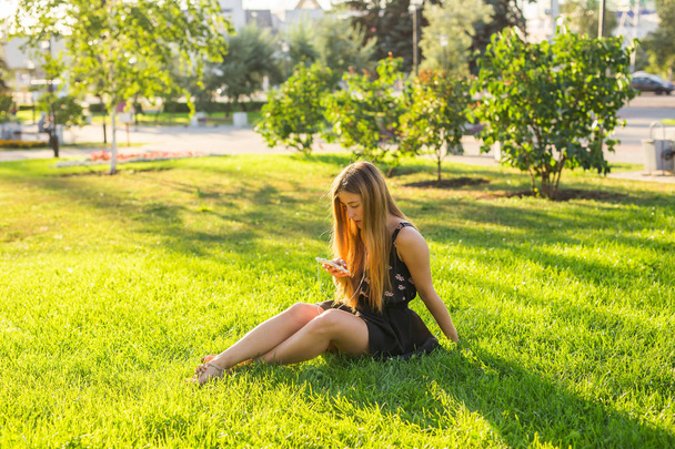 Kız yaz bir çayır üzerinde kulaklık ile akarsu müzik dinlemek. - Fotoğraf, Görsel