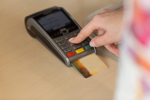 Ręka z machnięcia karty kredytowej za pośrednictwem terminala do płatności w kawiarni. - Zdjęcie, obraz