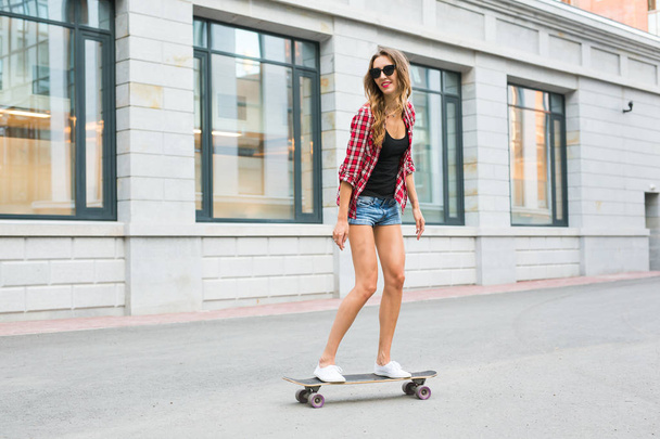 letnie wakacje, sport ekstremalny i koncepcja ludzie - szczęśliwy Dziewczyna jazda Nowoczesna deskorolka na miasto ulica - Zdjęcie, obraz