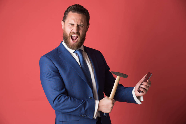 shouting businessman crushing mobile phone with hammer, overtime, crash test - Foto, afbeelding