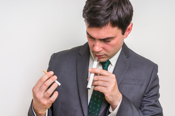 Uomo d'affari sta confrontando sigaretta elettronica e tabacco cigare
 - Foto, immagini