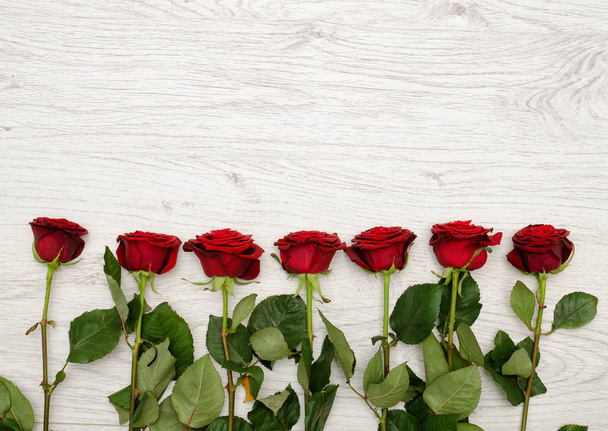 Tummanpunainen ruusu on kevyt puinen tausta reunalla runko, ylhäältä. Tekstitila
 - Valokuva, kuva