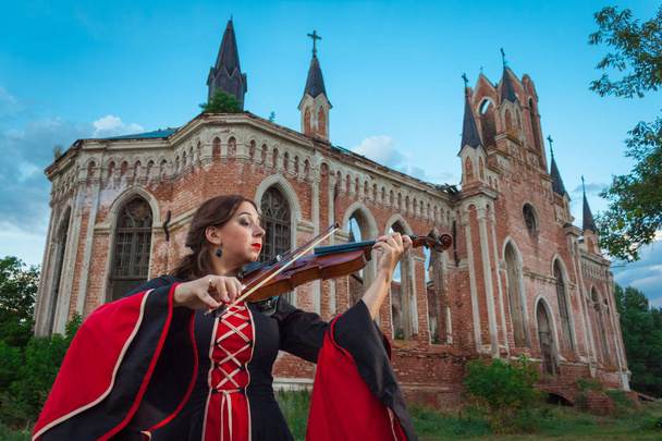 Музыкант играет на скрипке возле старого замка
 - Фото, изображение