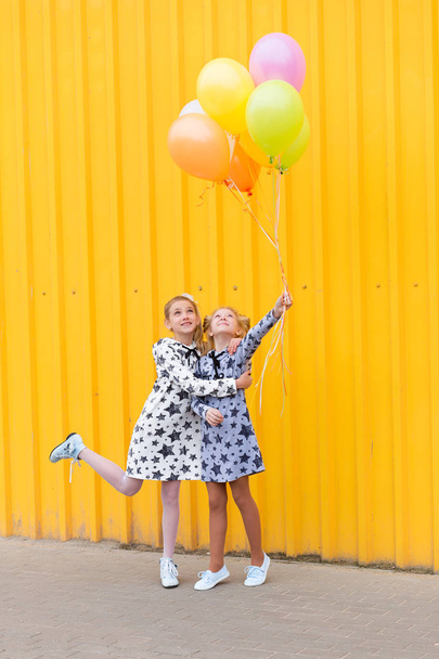 Πορτραίτο των κοριτσιών με μπαλόνια σε κίτρινο φόντο - Φωτογραφία, εικόνα