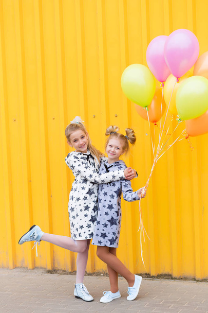 Πορτραίτο των κοριτσιών με μπαλόνια σε κίτρινο φόντο - Φωτογραφία, εικόνα
