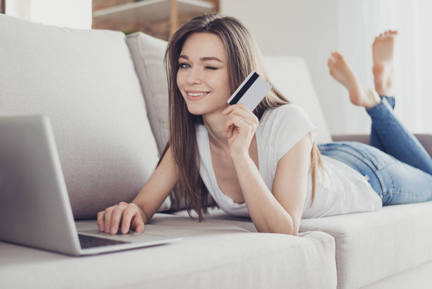Happy young woman showing credit card and doing internet online  - 写真・画像