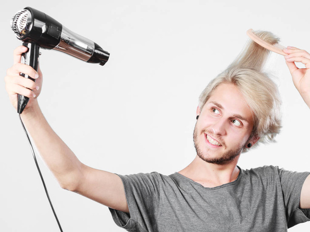 Young man drying hair with hairdryer - Foto, Bild