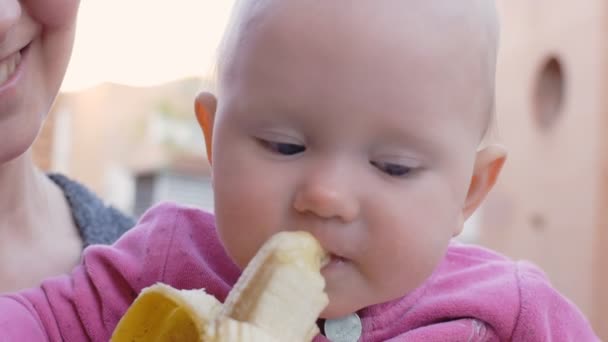 Dítě jíst banán z rukou matky - Záběry, video