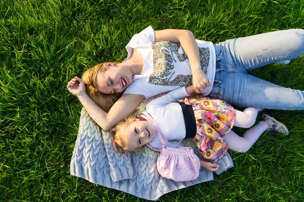 Ευτυχισμένη μητέρα και κόρη που χαμογελάει στο πάρκο έχοντας πικ-νικ - Φωτογραφία, εικόνα